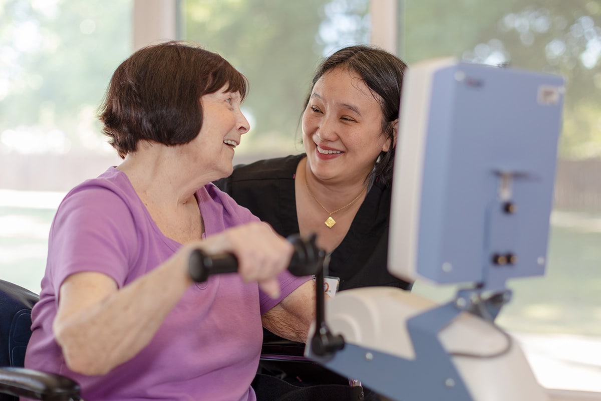 Patient on bike machine with a physical therapist